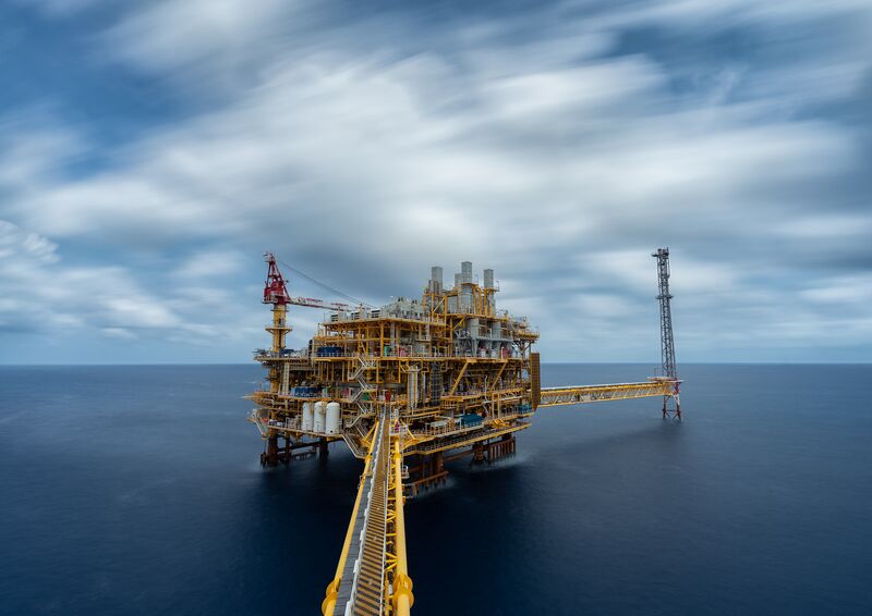 View of an offshore hydrocarbon production platform installed at sea, featuring industrial equipment and an access walkway